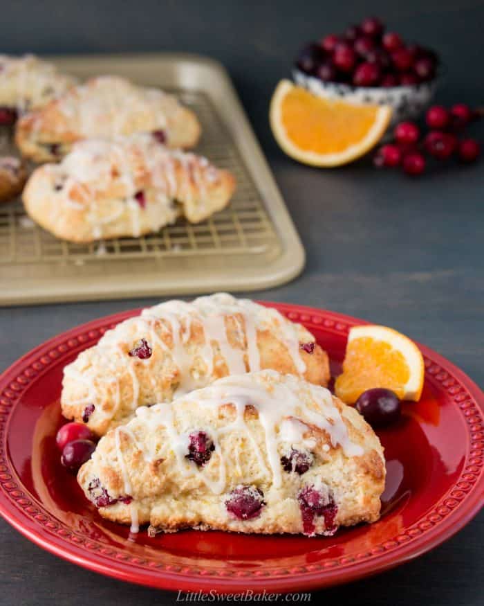 Two cranberry orange scones on a dark red plate.
