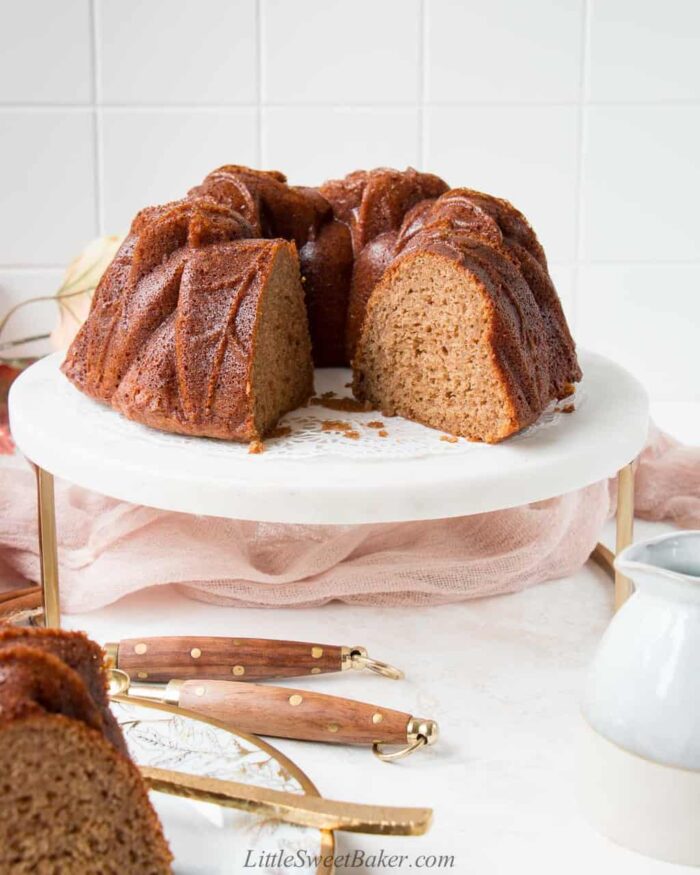 Apple cider bundt cake on a white and gold marble cake stand.
