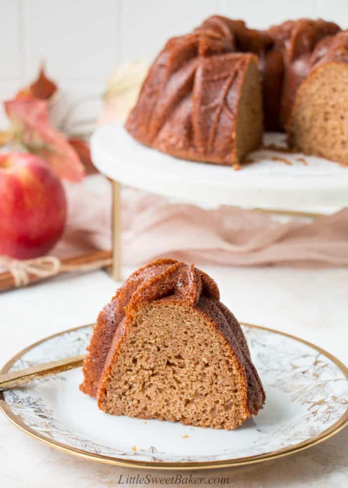 A slice of apple cider cake on a white and gold plate.