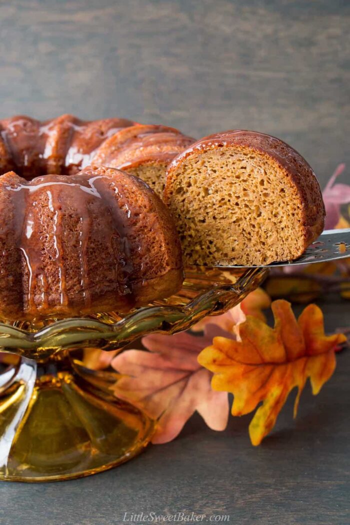 A pumpkin dump cake drizzled with caramel with a slice being removed.