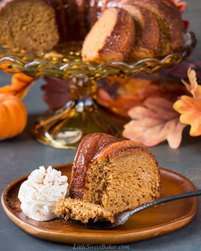 A slice of pumpkin dump cake on a brown wooden plate with whipped cream.