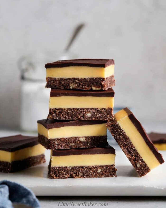 A tall stack of Nanaimo bars on a marble cutting board.