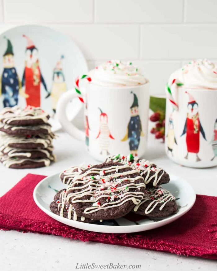 a plate of chocolate peppermint cookies on a red napkin with mugs of hot chocolate