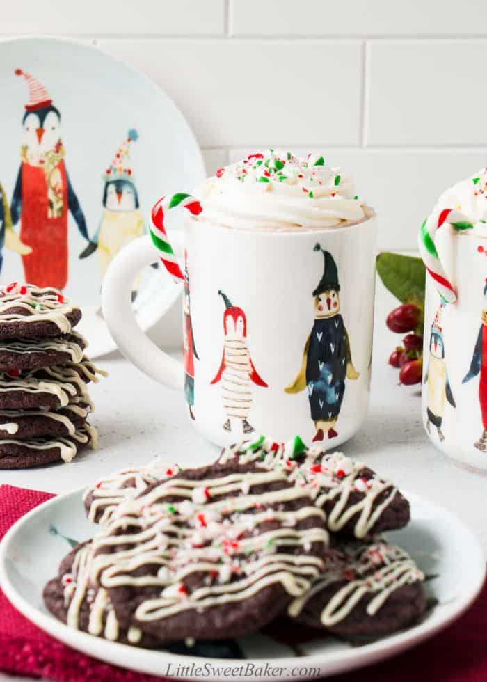 Peppermint hot chocolate in a penguin mug with a plate of cookies in front.