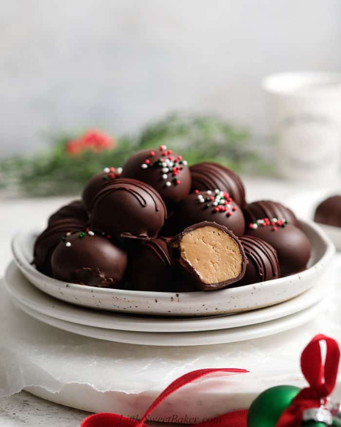 Peanut butter balls on a stack of white plates.