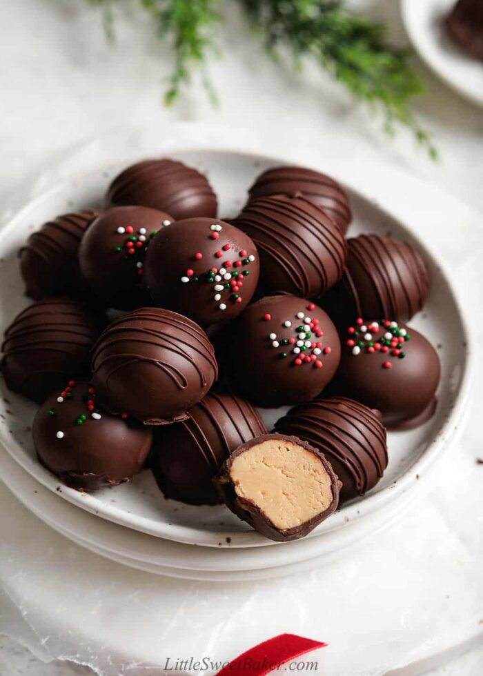 Peanut butter balls on a white speckled plate with one cut in half.