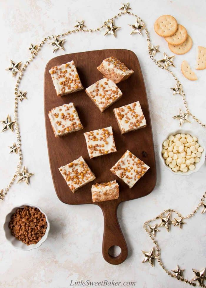 Skor bars with ritz crackers topped with white chocolate on a wooden cutting board.
