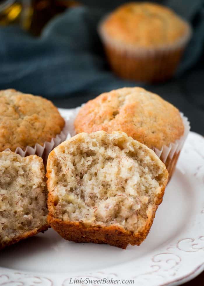 Banana bread muffins on a white plate with one broken in half.