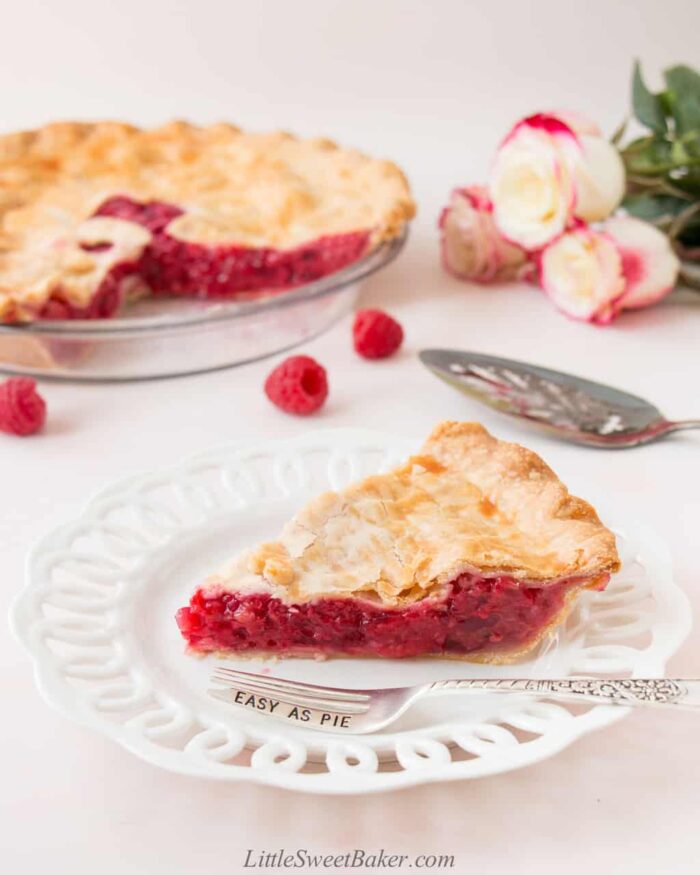 A slice of raspberry pie in a white plate with a silver fork.