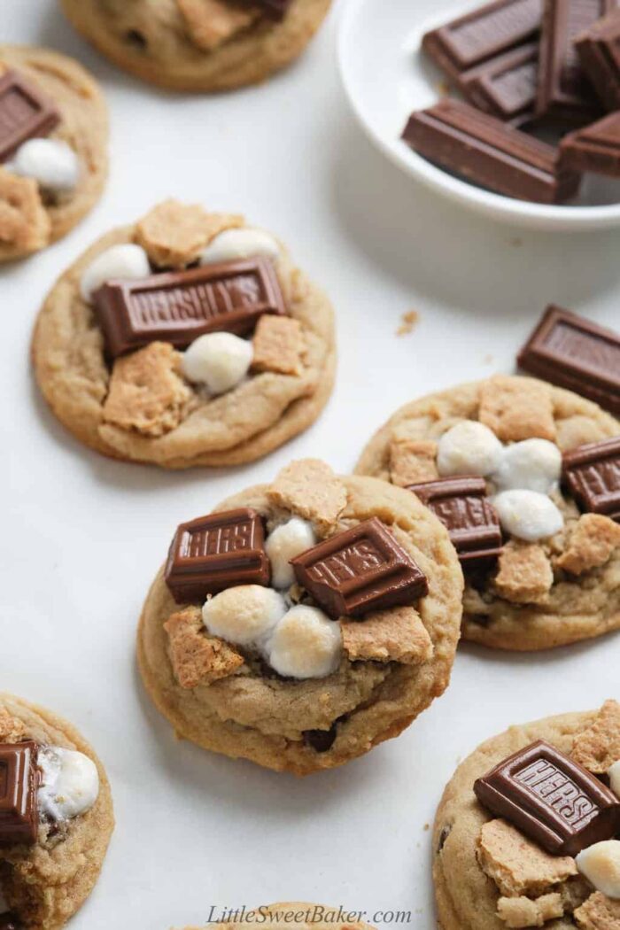 Soft and chewy s'mores cookies scattered on a white surface.