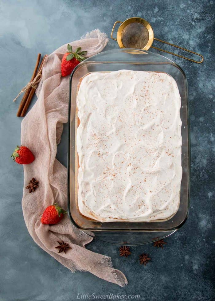 An overhead view of a whole tres leches cake on a dark blue surface.