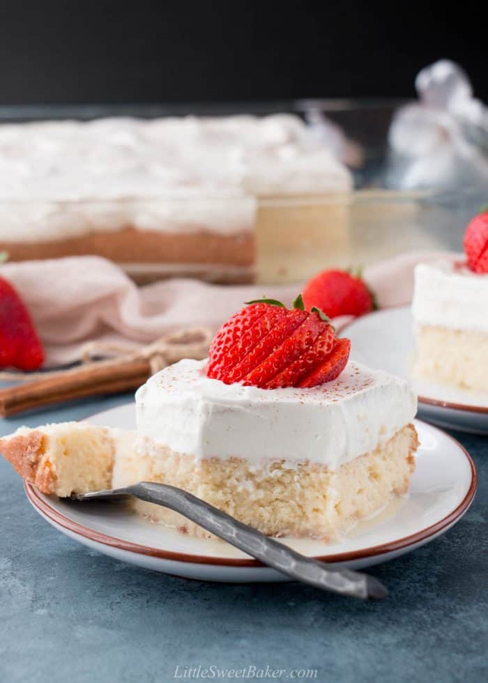 A slice of tres leches cake on a plate with a piece on a fork.