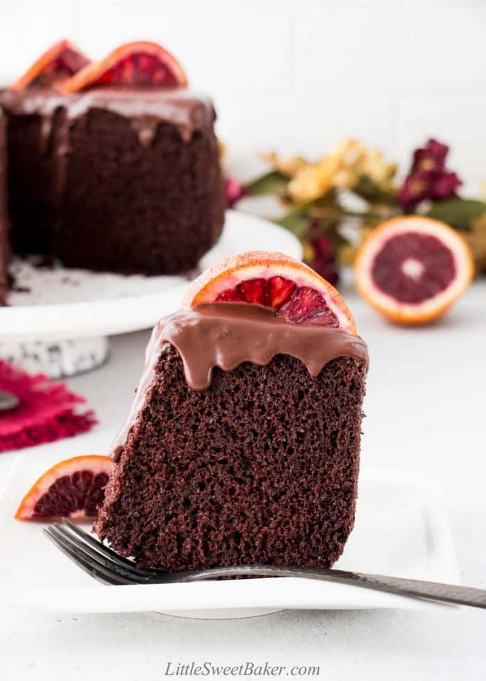 A slice of chocolate chiffon cake topped with chocolate ganache and an blood orange slice.