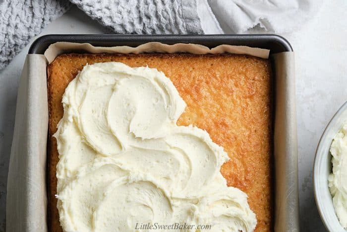 A vanilla cake partially topped with vanilla buttercream swirls.