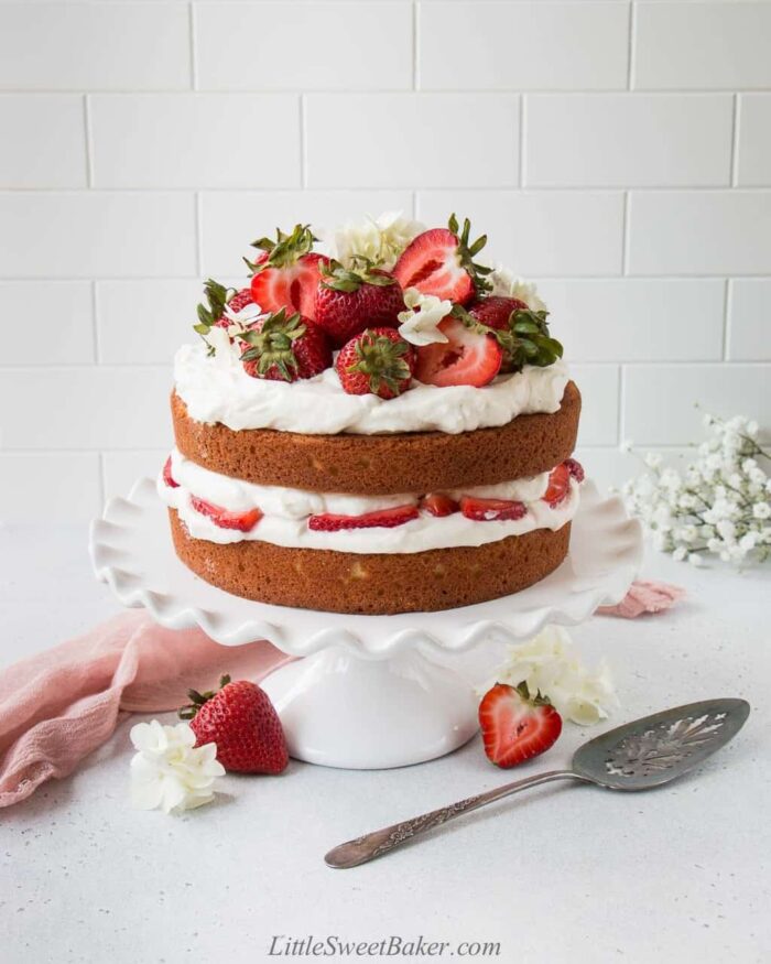A strawberry shortcake cake on a white cake stand