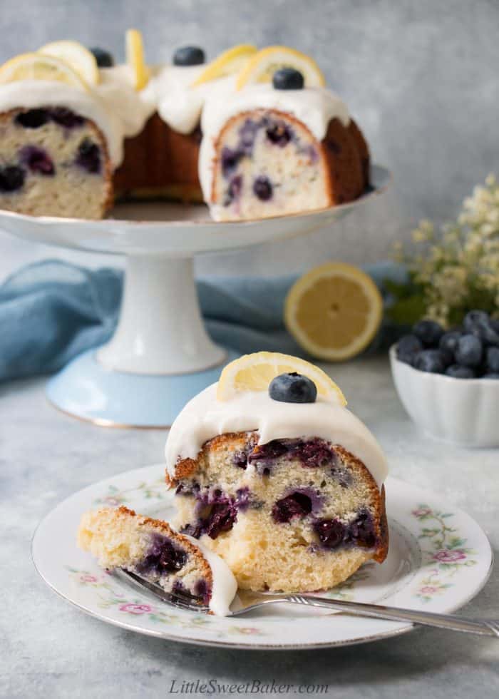 a slice of lemon blueberry cake with cream cheese frosting on a vintage floral plate