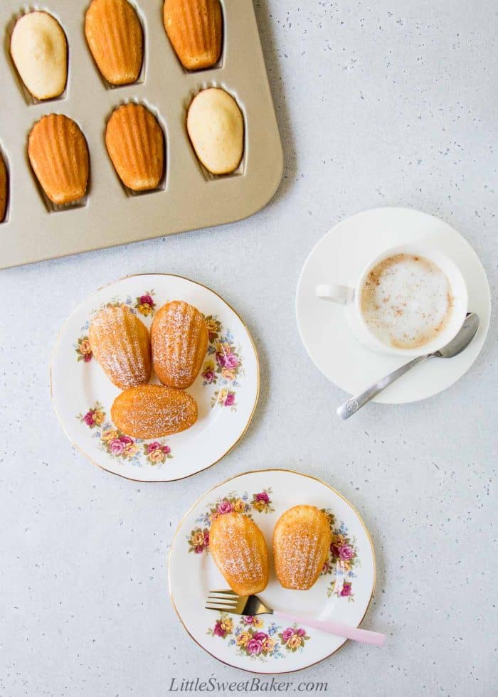 Madeleine cookies on dessert plates and baking pan with a cup of coffee.