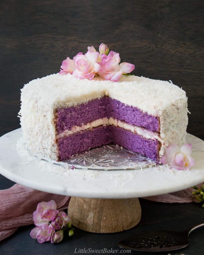 Ube cake on a cake stand with a quarter of it cut out