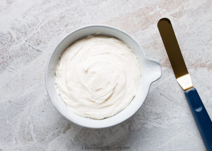 A bowl of coconut frosting with a gold offset spatula.