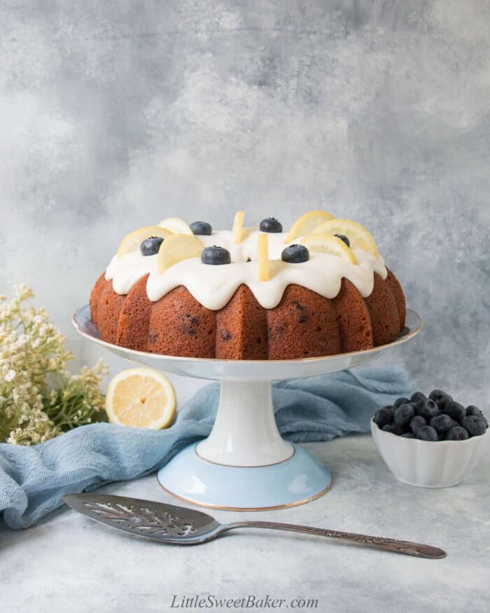 A lemon blueberry cake with cream cheese frosting on a cake stand.