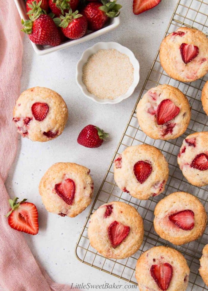 An overhead view of strawberry muffins on a cooling rack and on the side