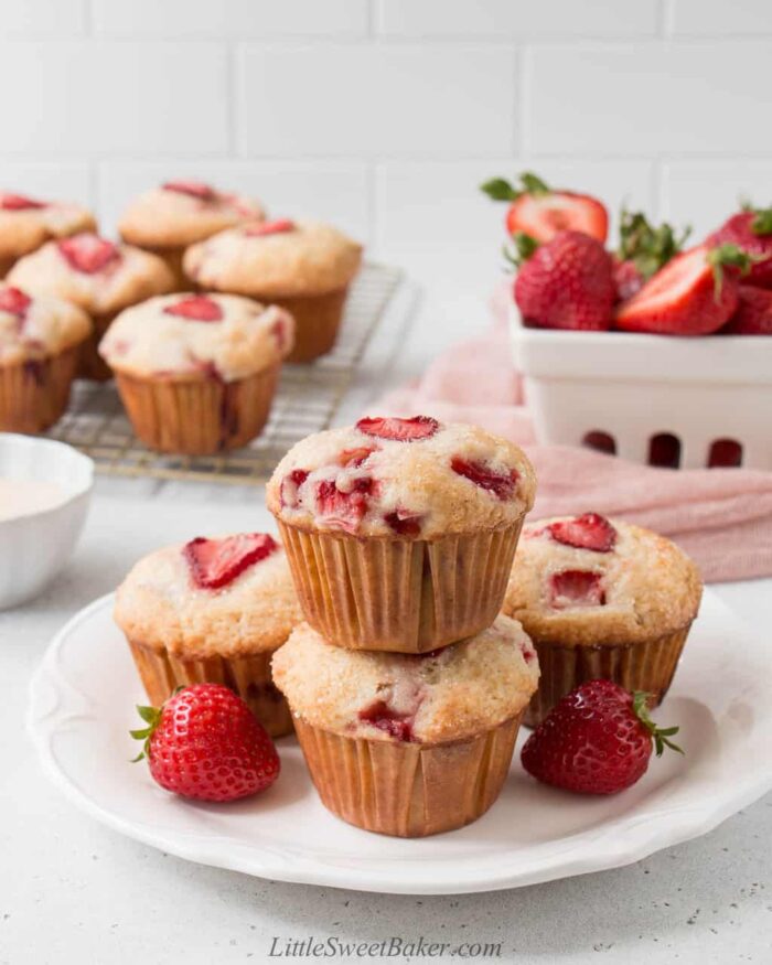 Strawberry muffins on a white plate and on a cooling rack in the background.