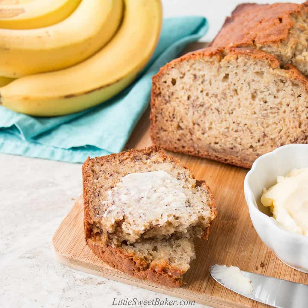 Banana bread on a cutting board with a buttered slice.