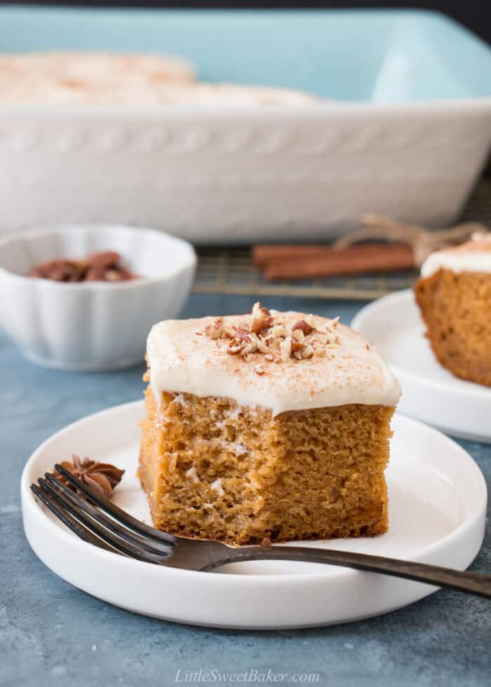 A slice of pumpkin cake on a white plate with a black fork.