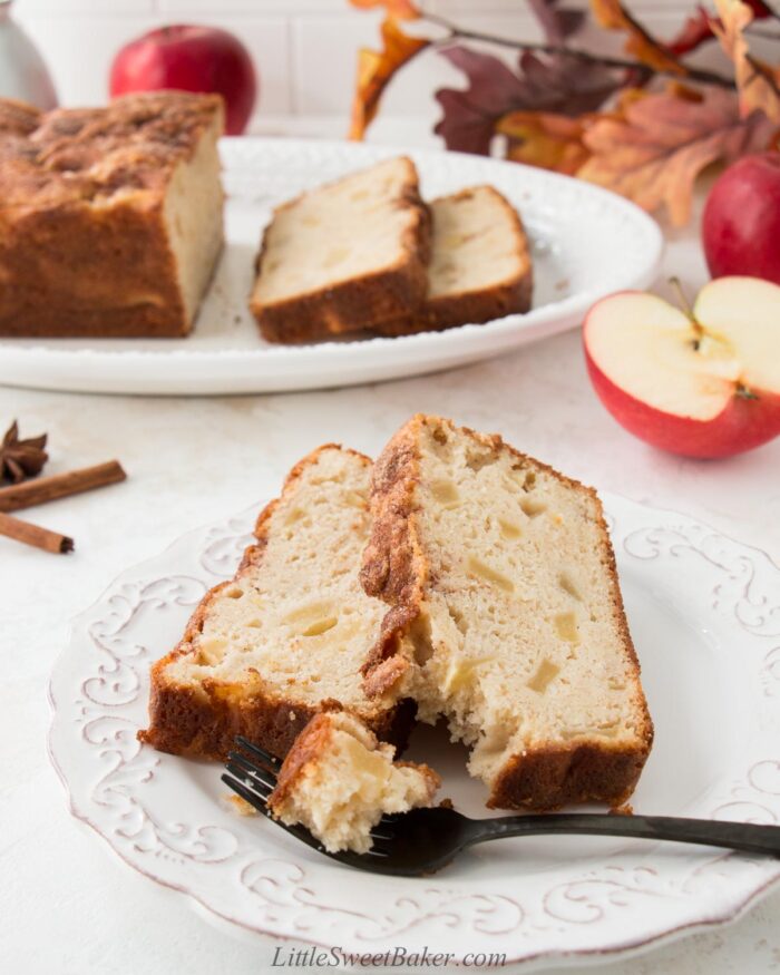 Two slice of apple bread on a white plate with a piece on a fork.