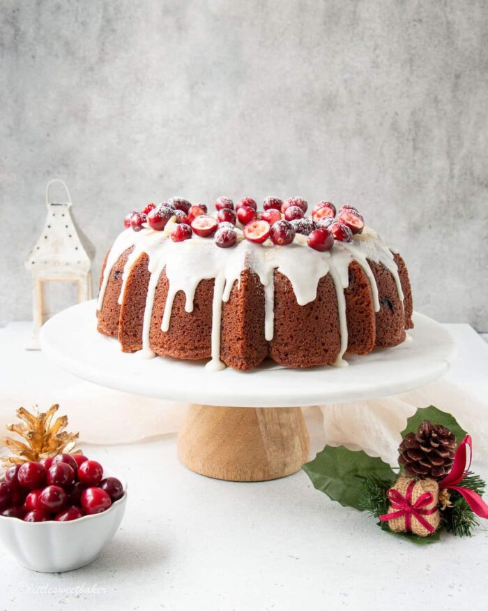 cranberry cake topped with glaze and cranberries on a cake stand