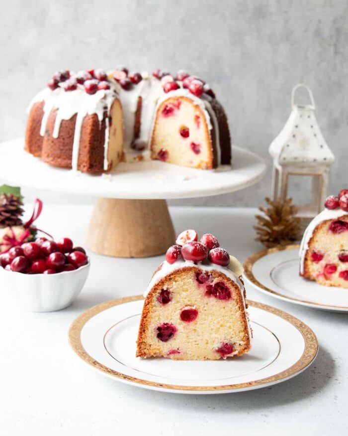 Cranberry cake on a cake stand with two slices on plates