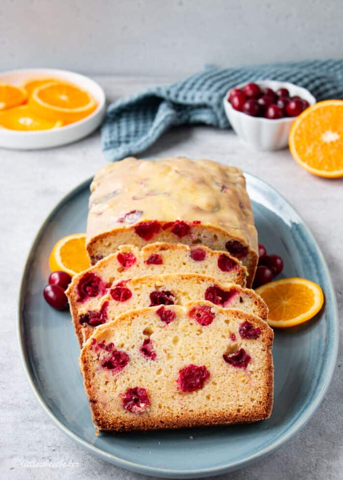 A loaf of cranberry orange bread on a blue serving plate.