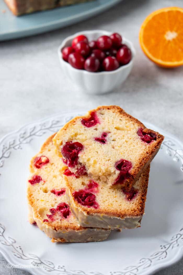 Three slices of cranberry orange bread on a light grey plate.