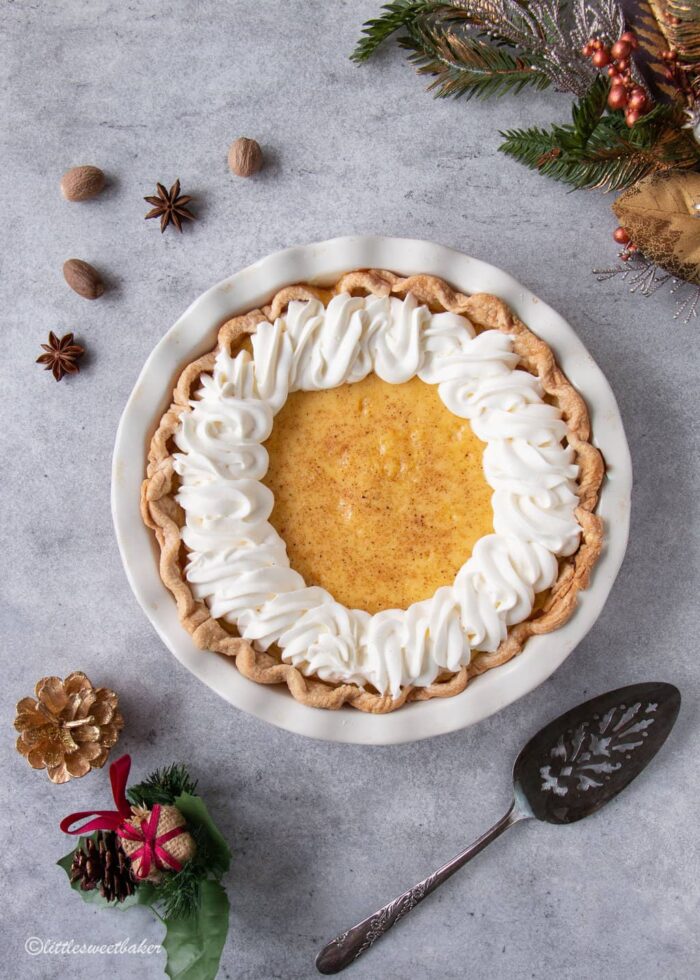 An eggnog custard pie topped with whipped cream along the edges