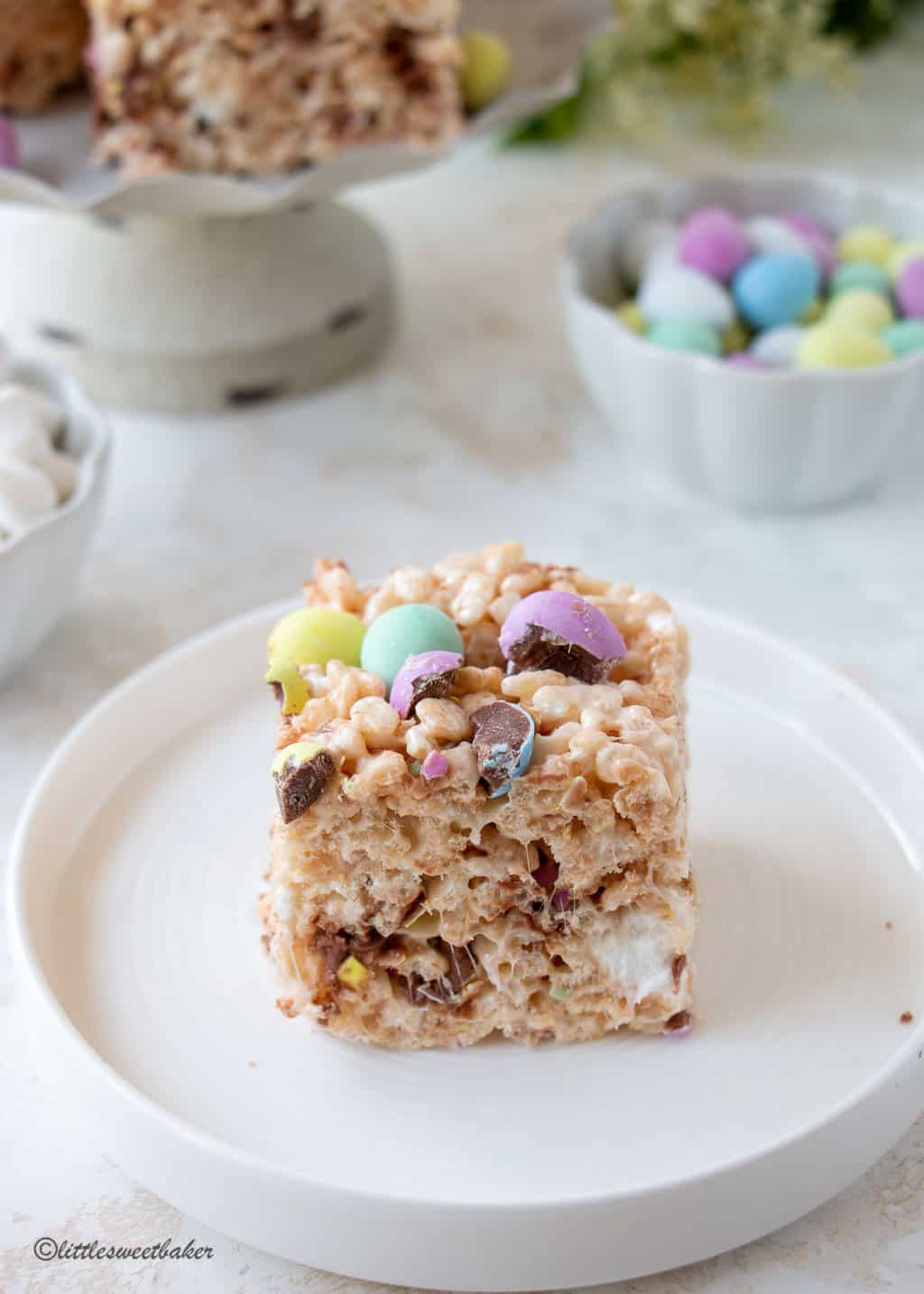 An Easter Rice Krispie square with mini eggs on a white plate