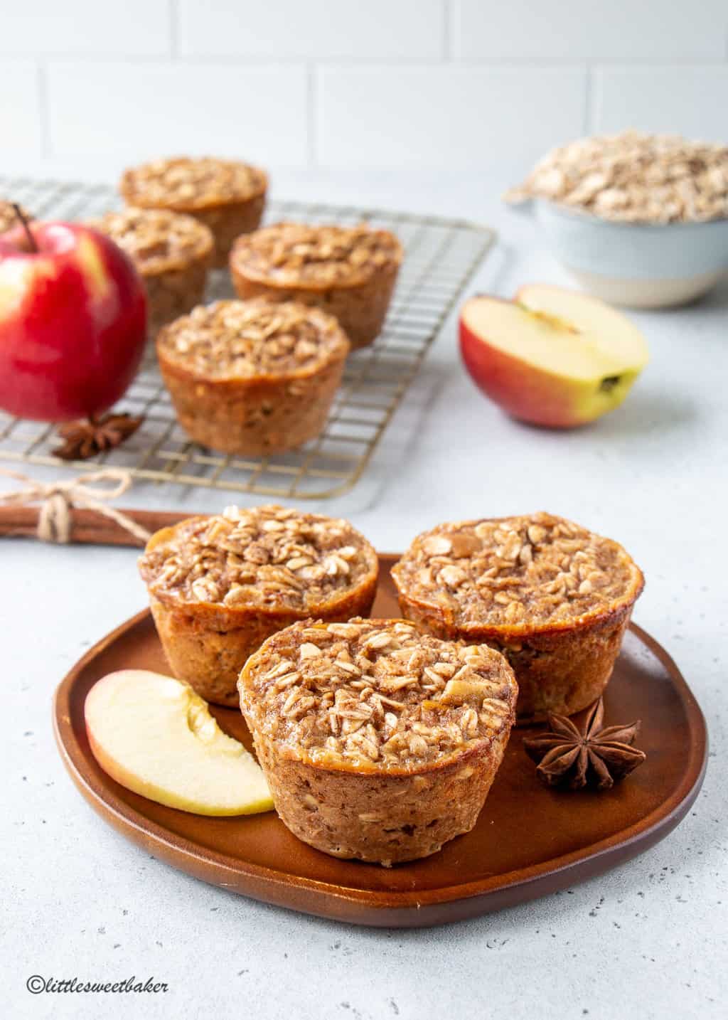 Three baked apple oatmeal cups on a wooden plate.