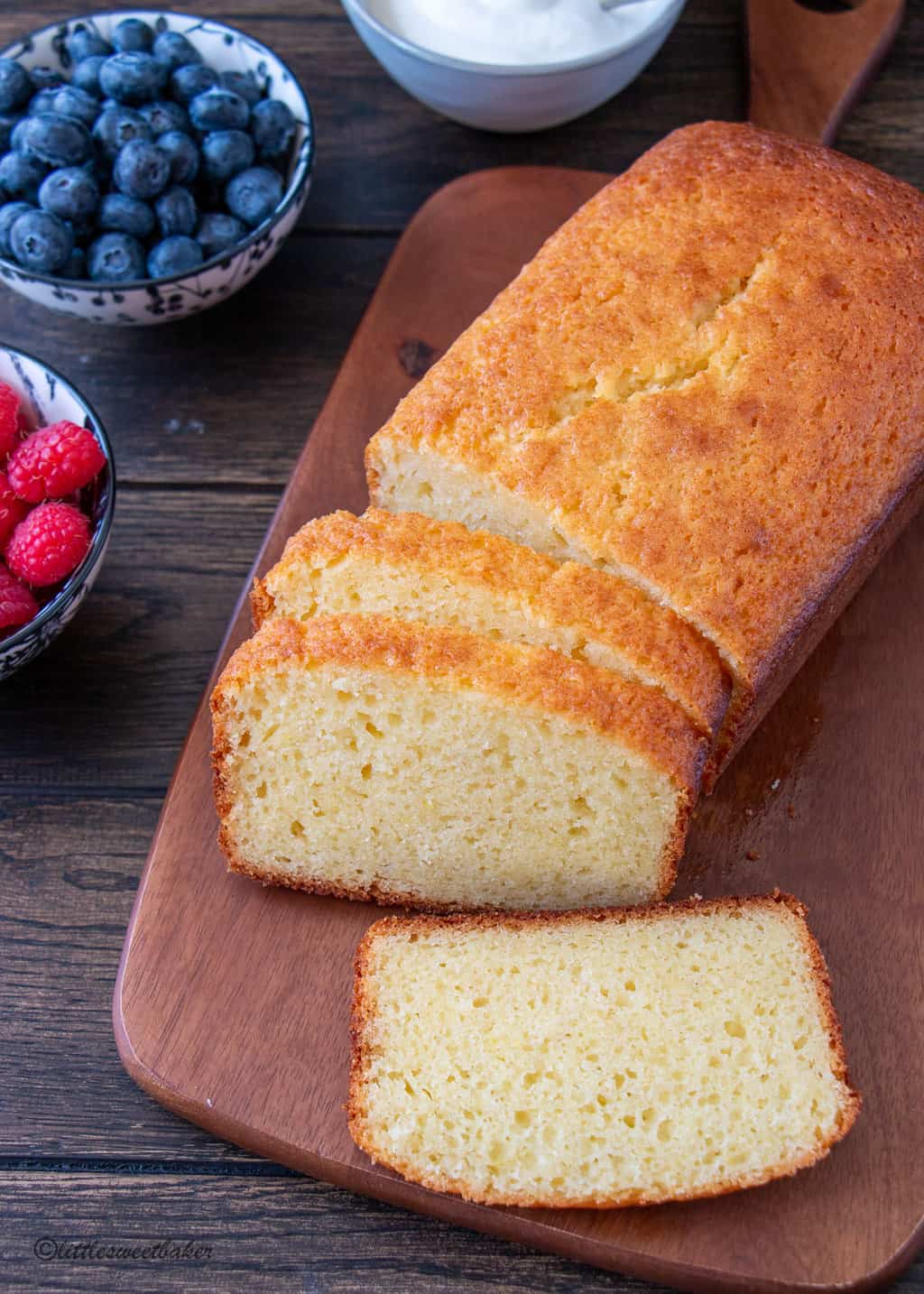 A loaf of French yogurt cake sliced on a wooden cutting board.