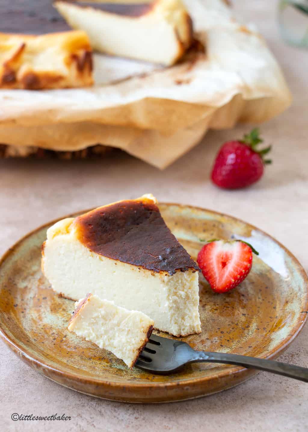 A slice of basque cheesecake on a plate with a piece on a fork.
