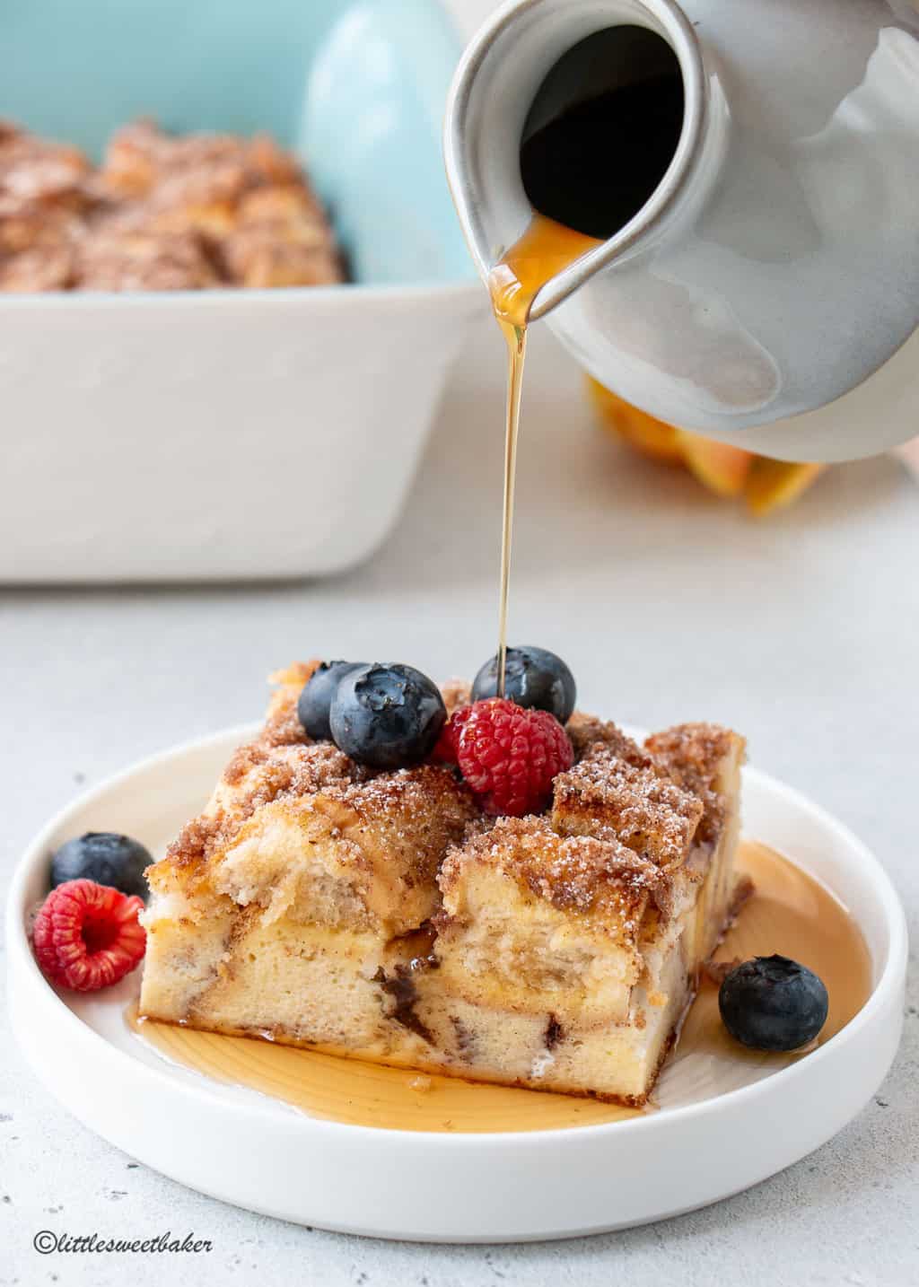 a piece of French toast topped with berries and maple syrup poured on top