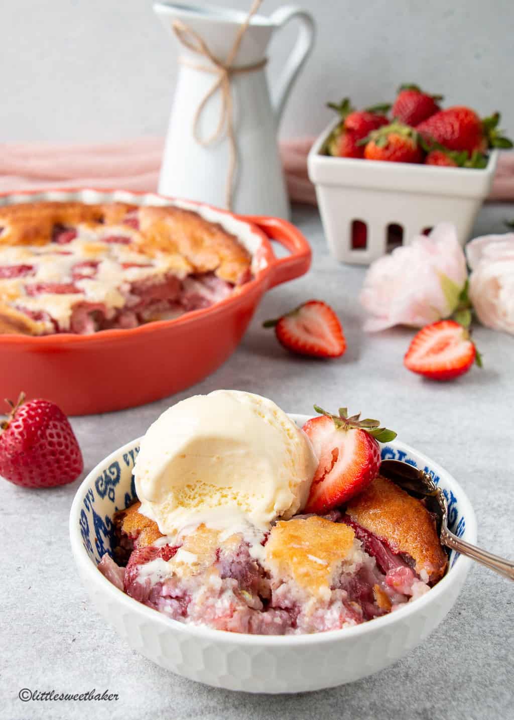 A partially eaten bowl of strawberry cobbler with ice cream