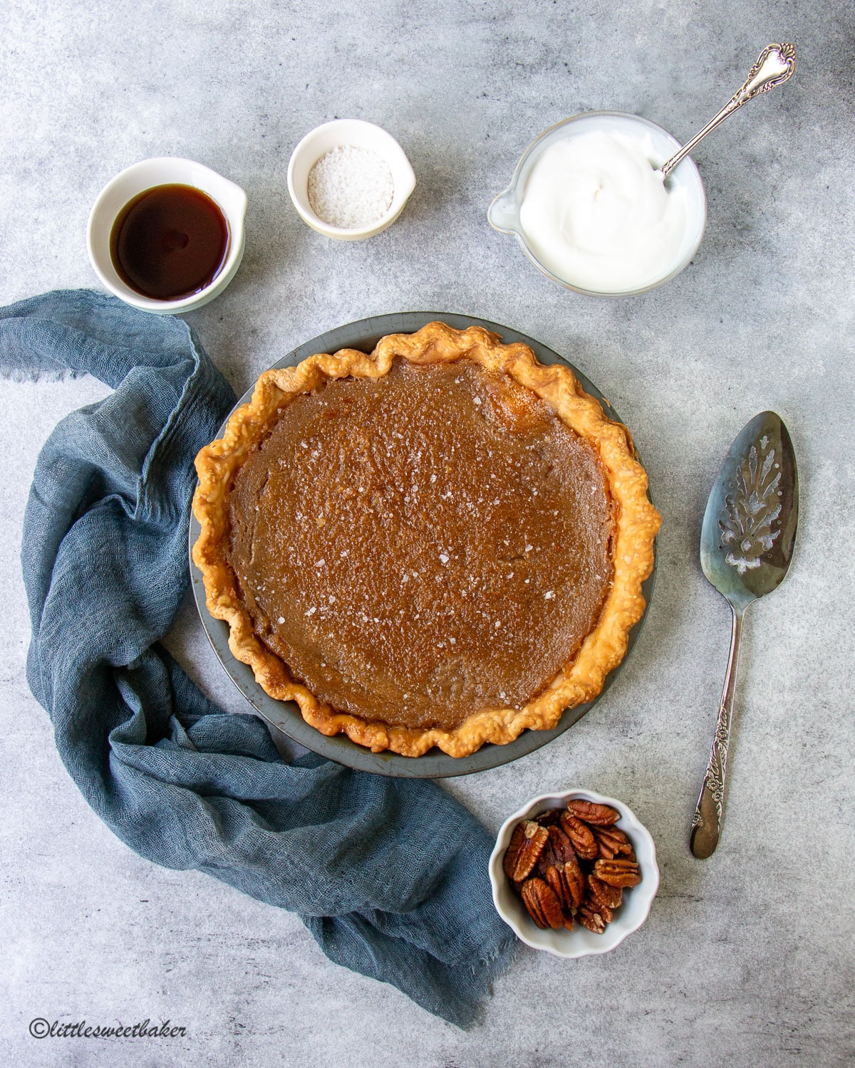 Maple syrup pie surrounded by ingredients and a blue napkin.
