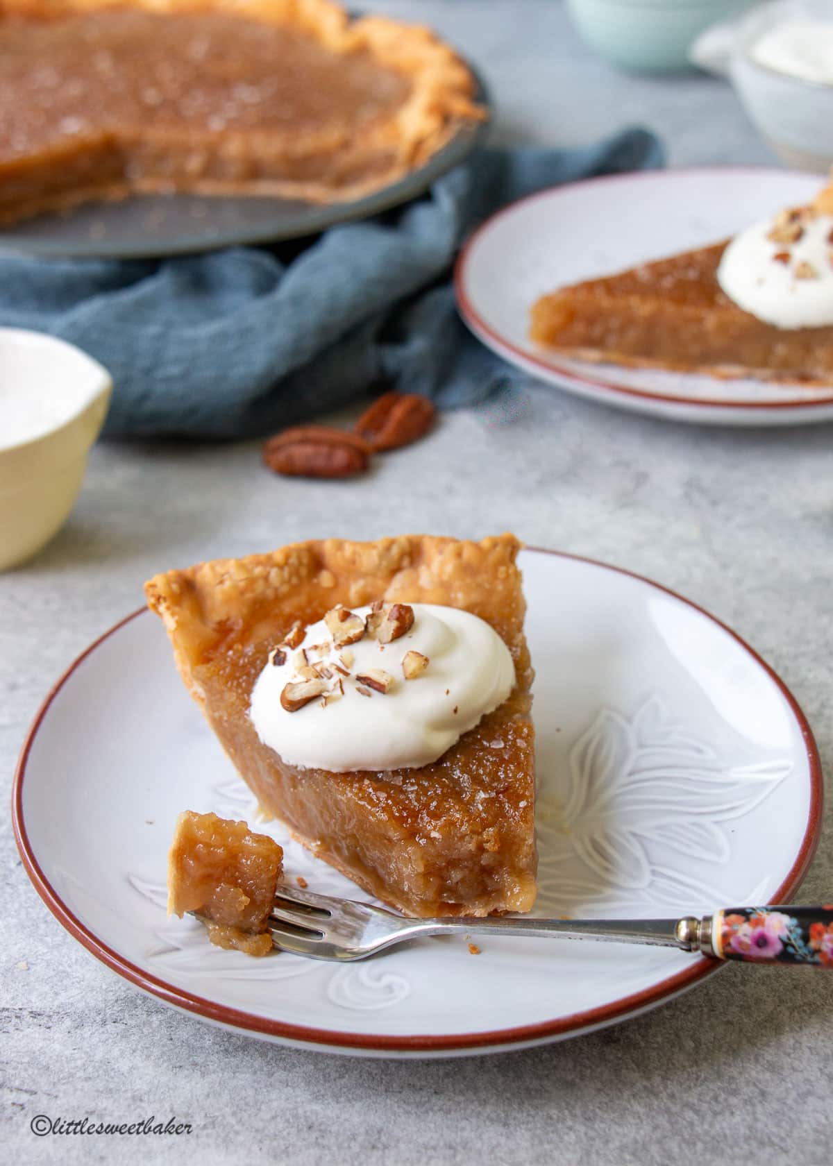 A slice of maple syrup pie topped with whipped cream with a piece on a fork.