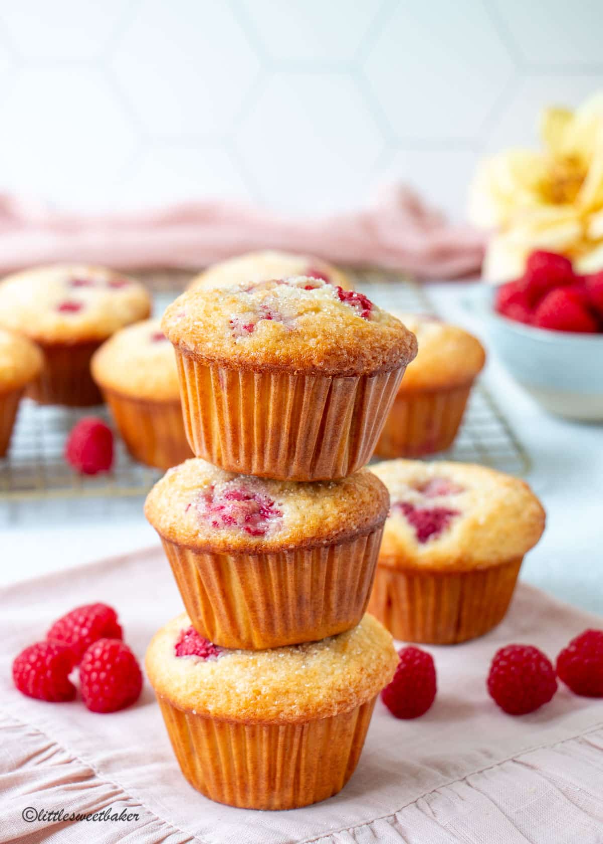 A tower of 3 raspberry muffins on a pink ruffle napkin.