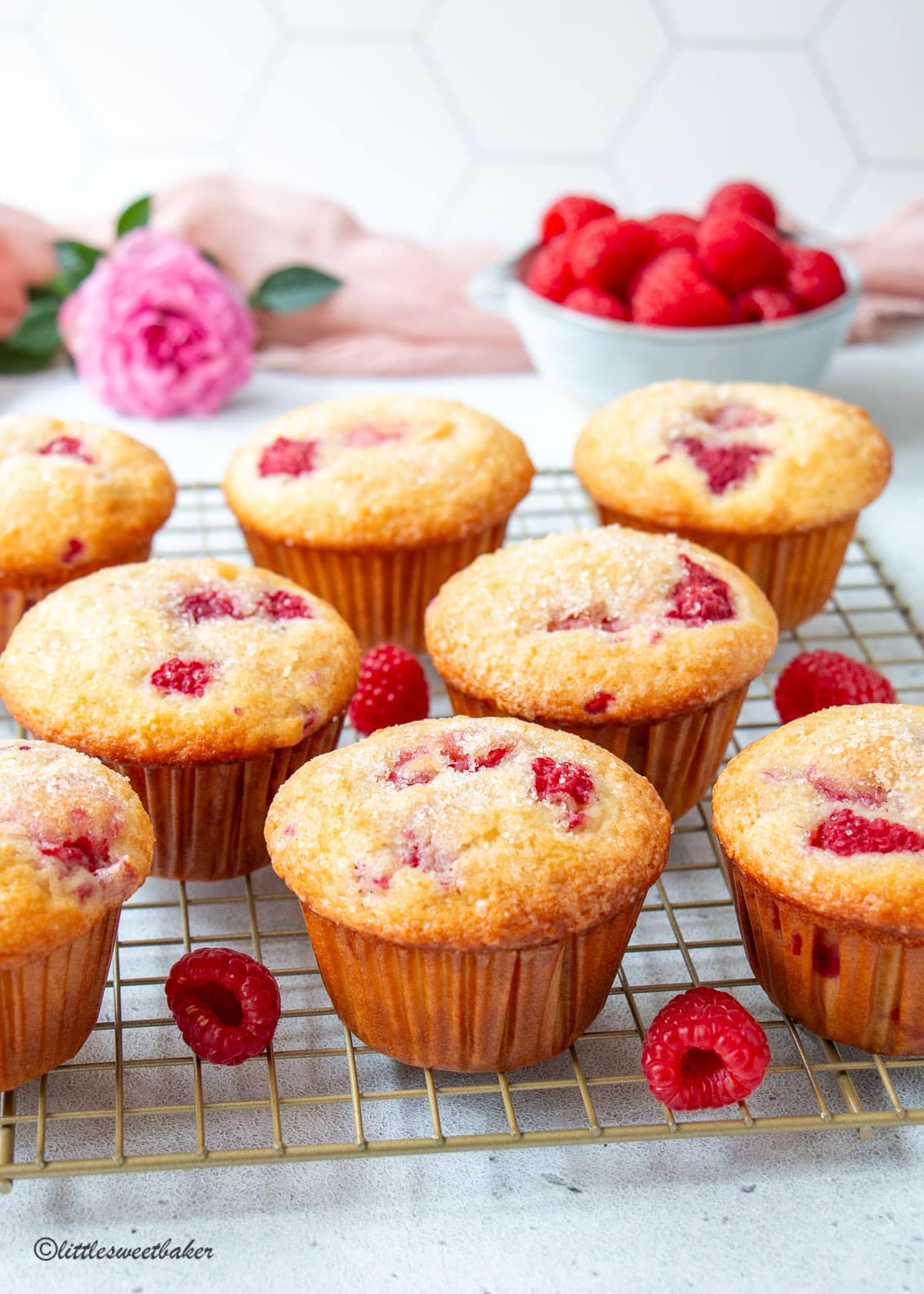Fresh raspberry muffins on a gold cooling rack.