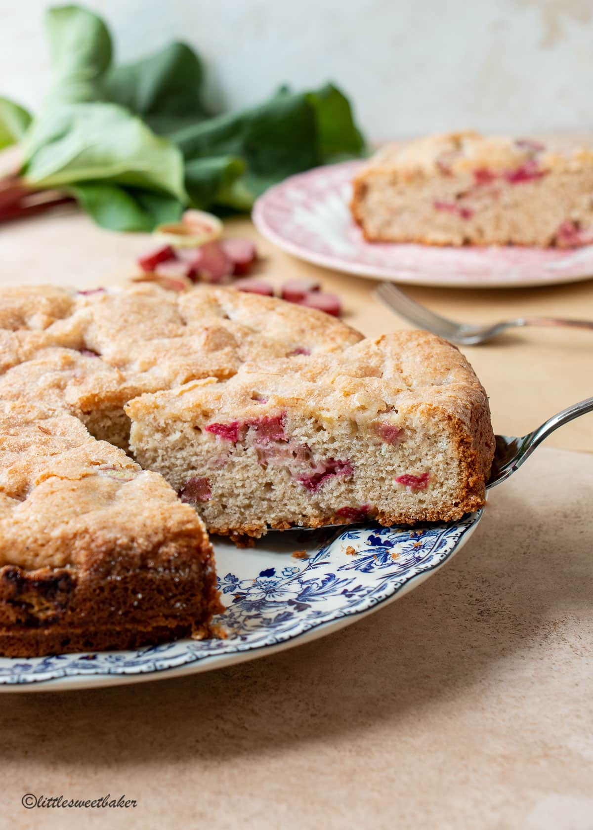 A slice of rhubarb cake being removed from the rest of the cake.