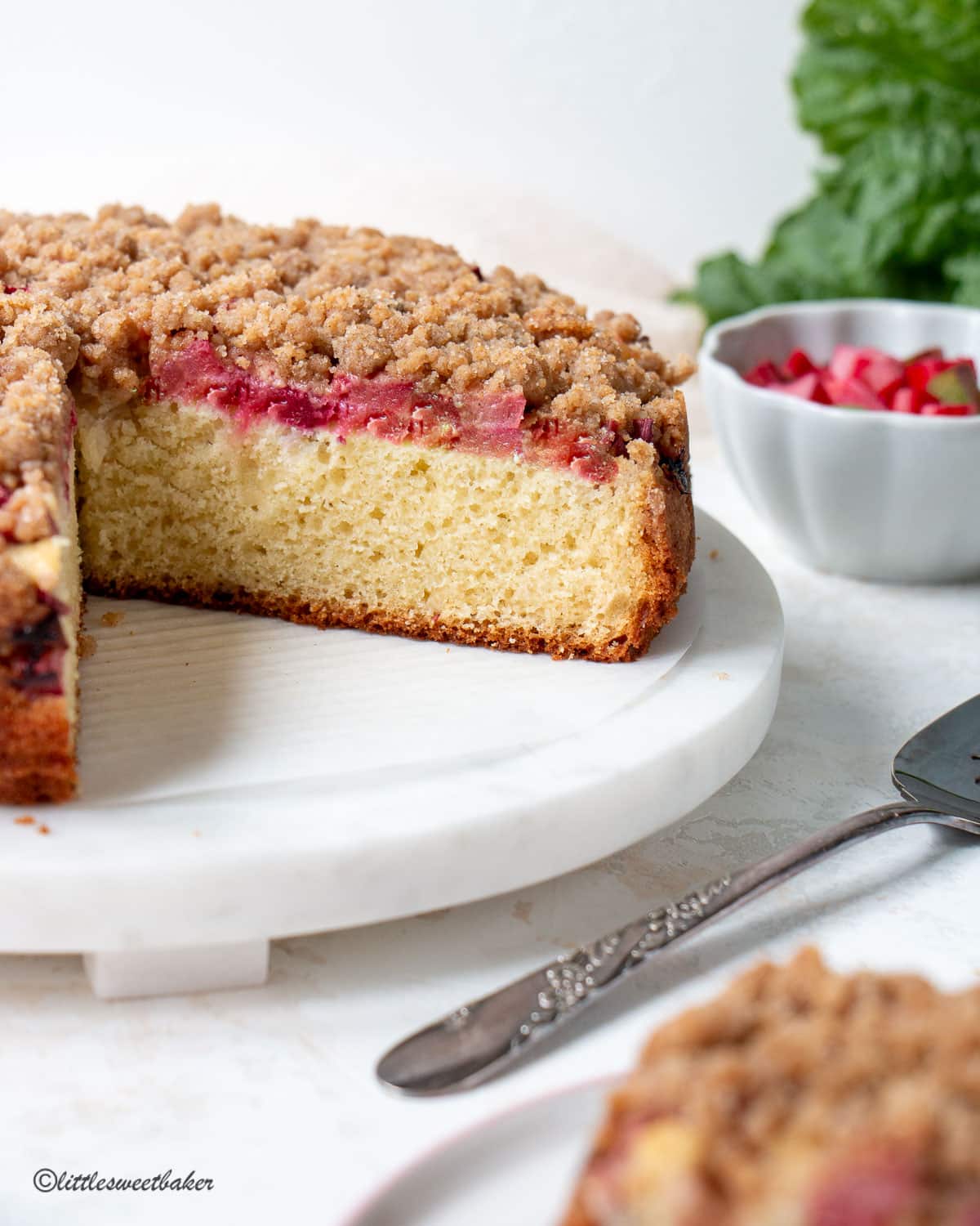 A rhubarb coffee cake on a white marble serving plate.