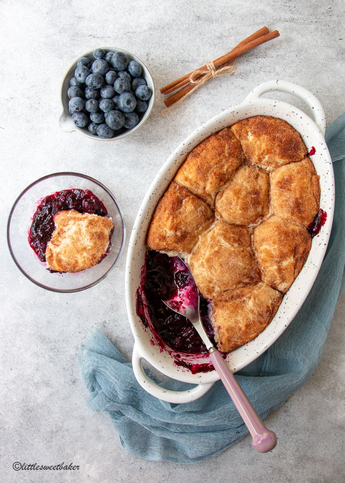 A casserole dish of blueberry cobbler with some in a bowl