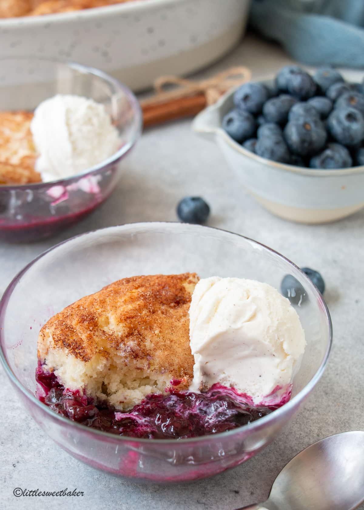 A clear bowl of blueberry cobbler with ice cream.