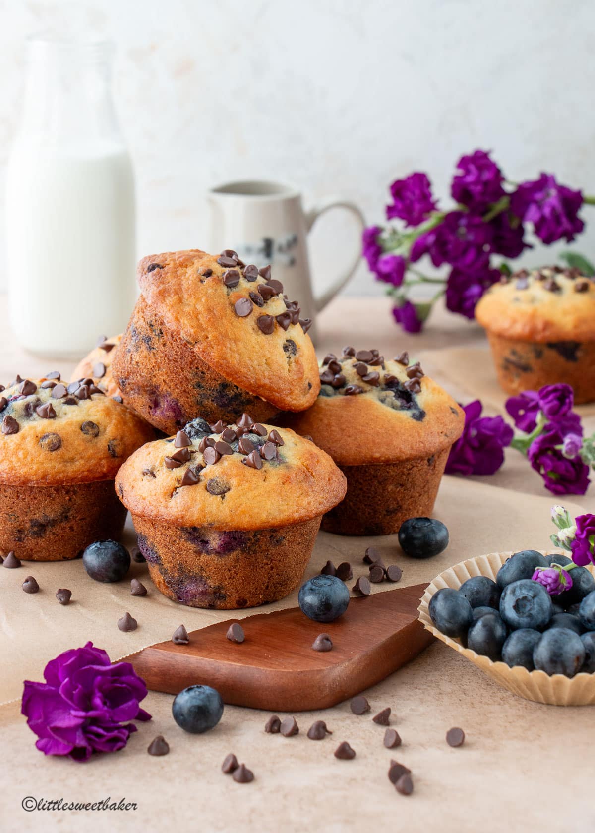 Blueberry chocolate chip muffins on a wooden cutting board.