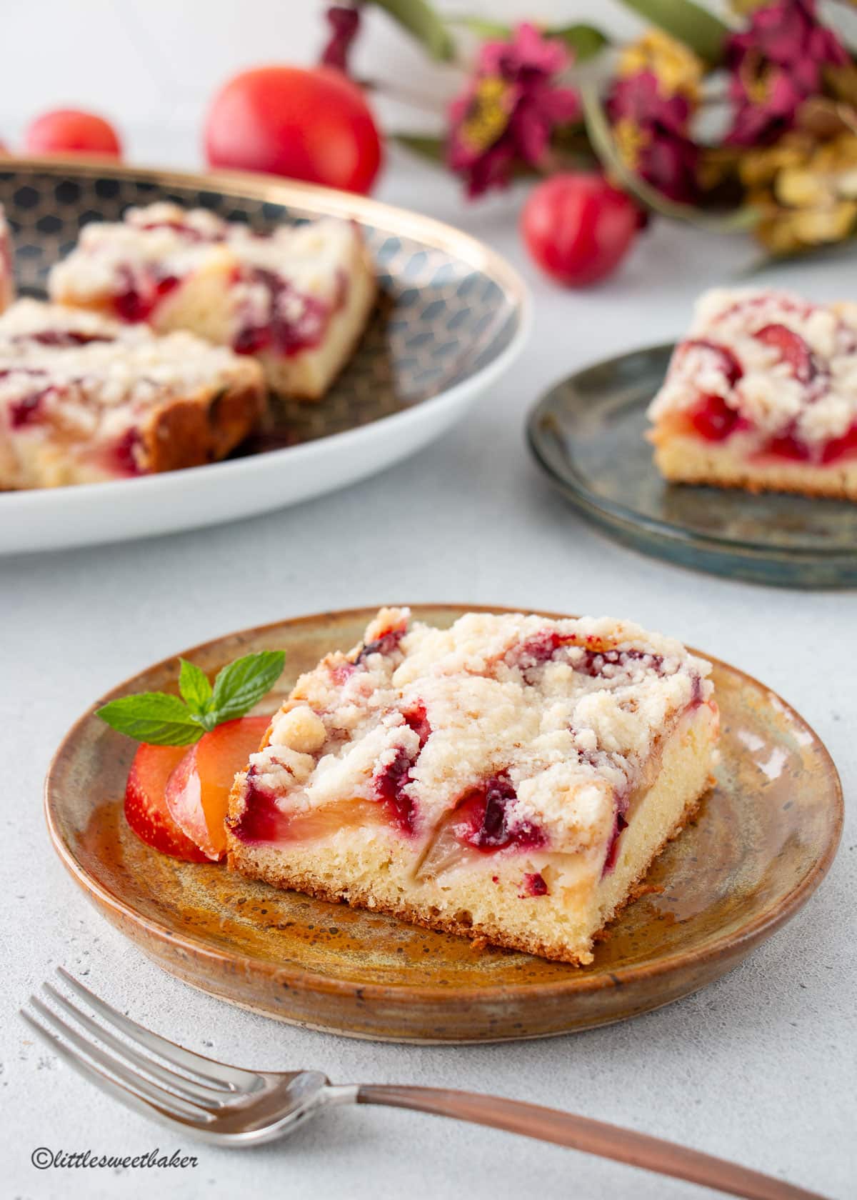 A slice of German plum cake on a brown pottery plate.